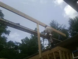 Carpenter setting a ridge beam over a new addition frame — Ice Dam Removal by Roofing Brothers in Axtell