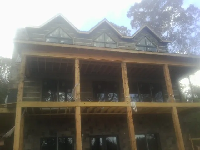 Dormers and porch framing on a large log home under construction — Roof Coating work by our crew in Axtell