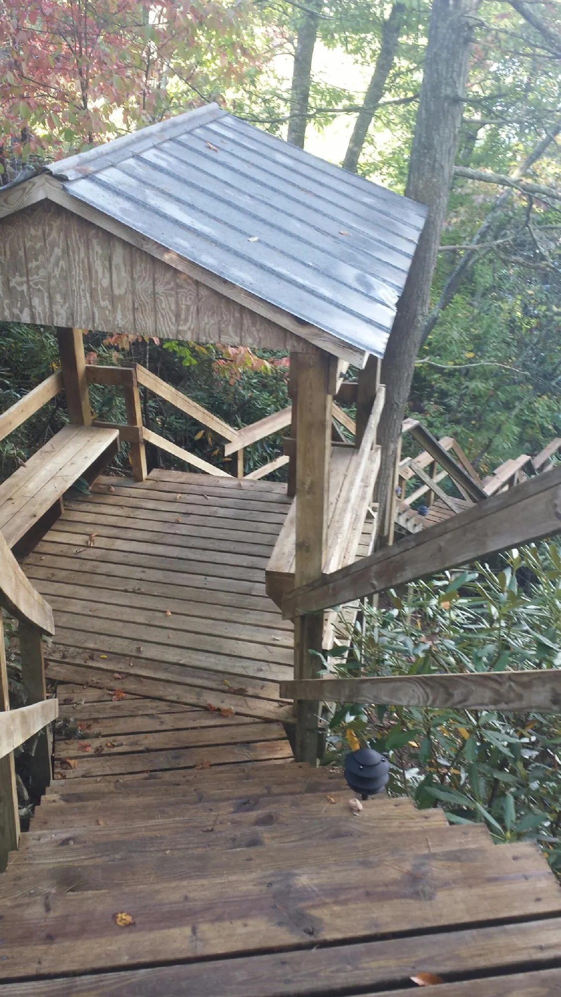 Metal roofed shelter over wooden steps on a wooded walkway — Skylight Repair & Installation work by our crew in Axtell