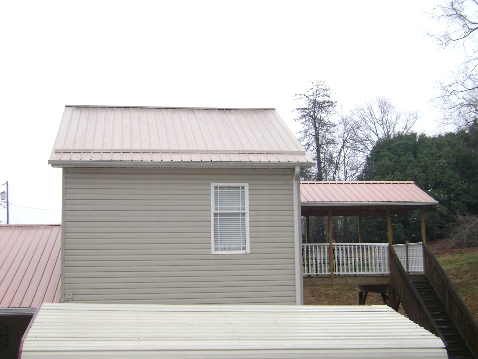 Tan metal roofs on a two story addition and attached porch, from a Roof Replacement job in Axtell