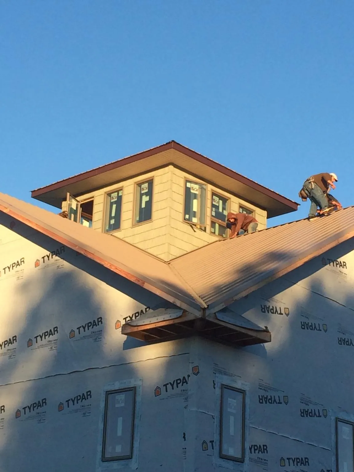 Roofers working around a rooftop cupola on a new metal roof at sunset — Roof Waterproofing in Axtell by Roofing Brothers